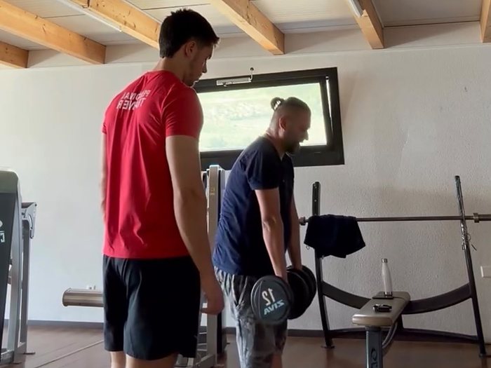 Nicolau Roque supervise la technique d'un client sur charge libre avec barre, dans une salle de sport en Valais